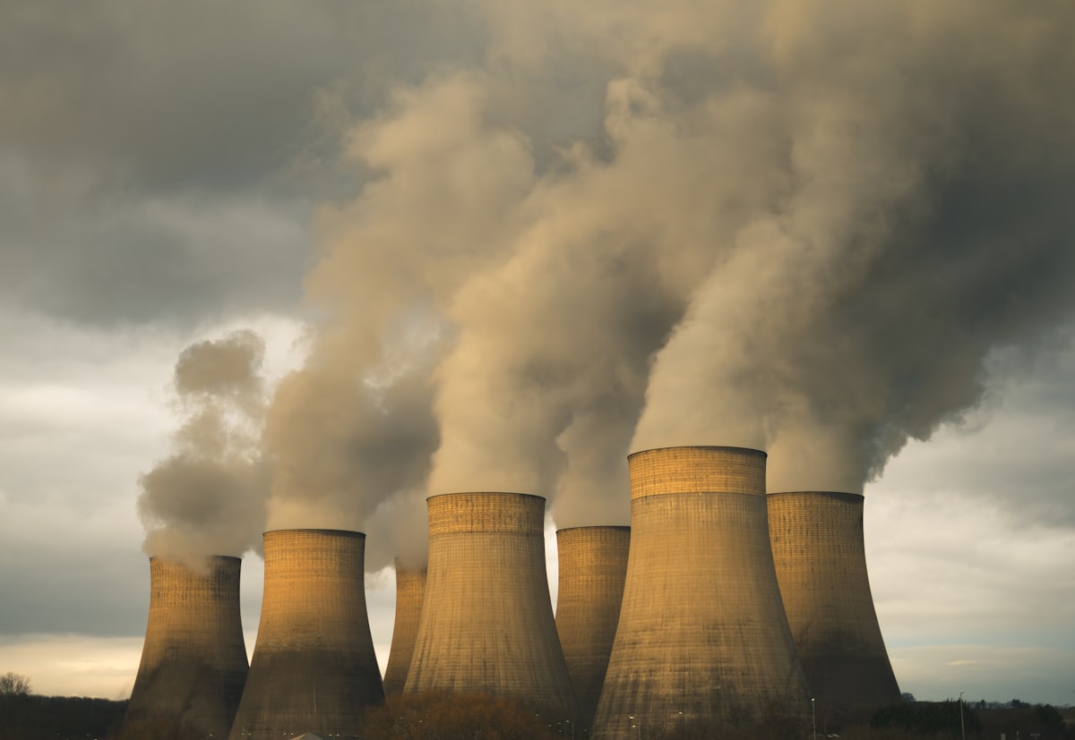 Coal power plant smokestacks emitting steam against a cloudy sky