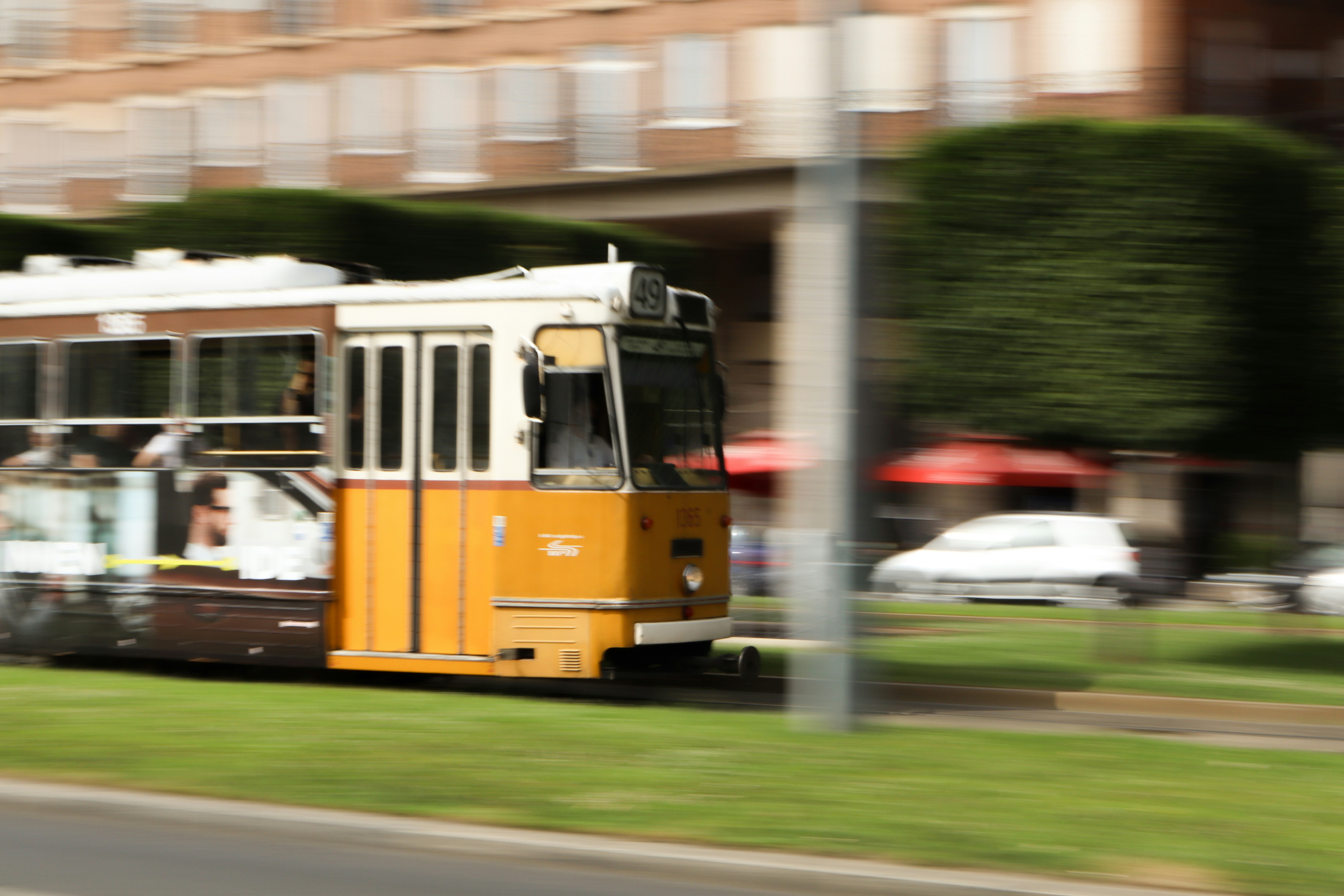 A yellow and white trolley traveling down a street