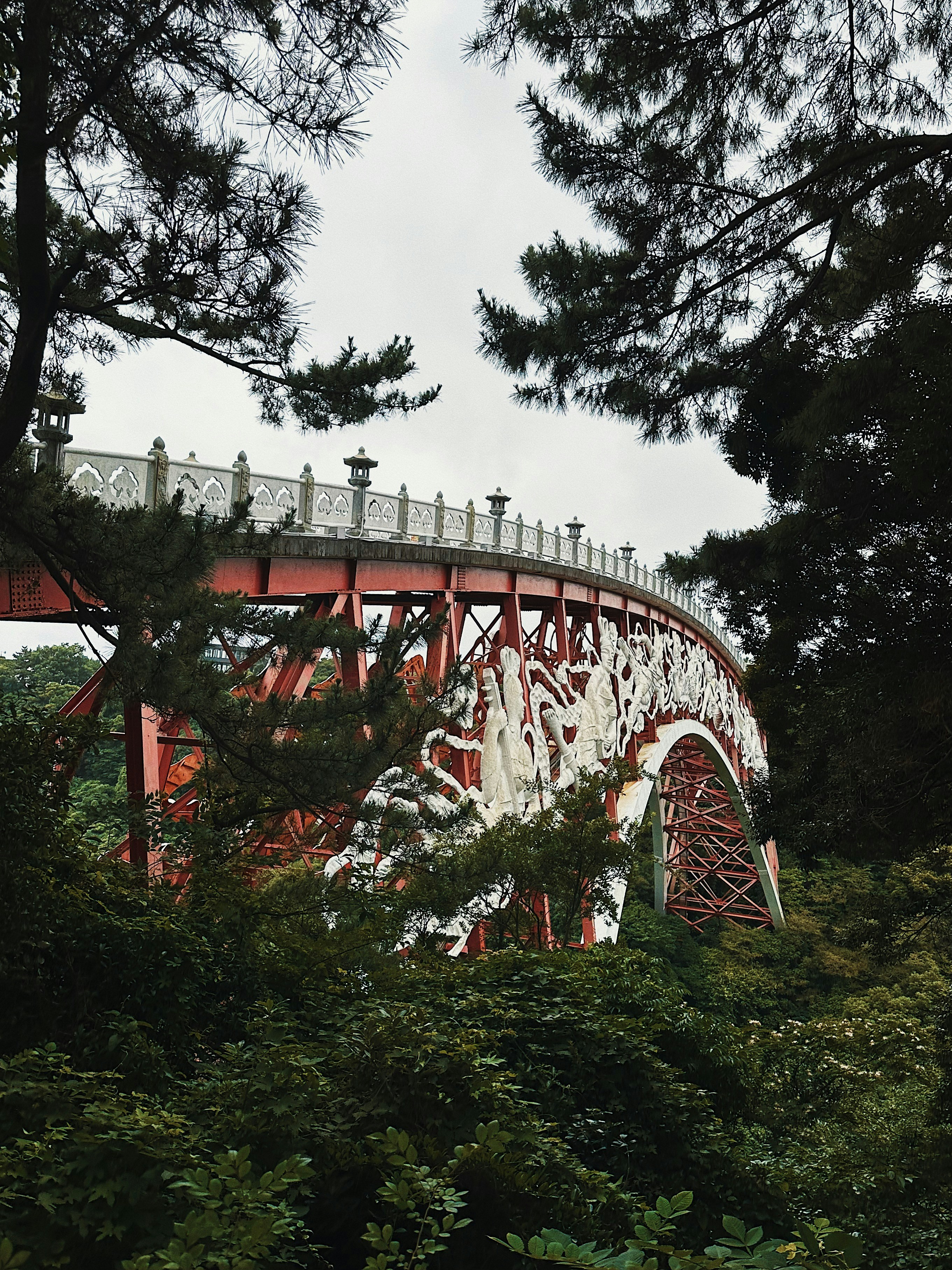 A red and white bridge over a lush green forest