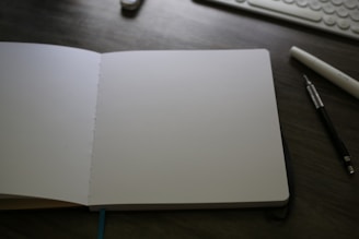 An open notebook sitting on a desk next to a keyboard