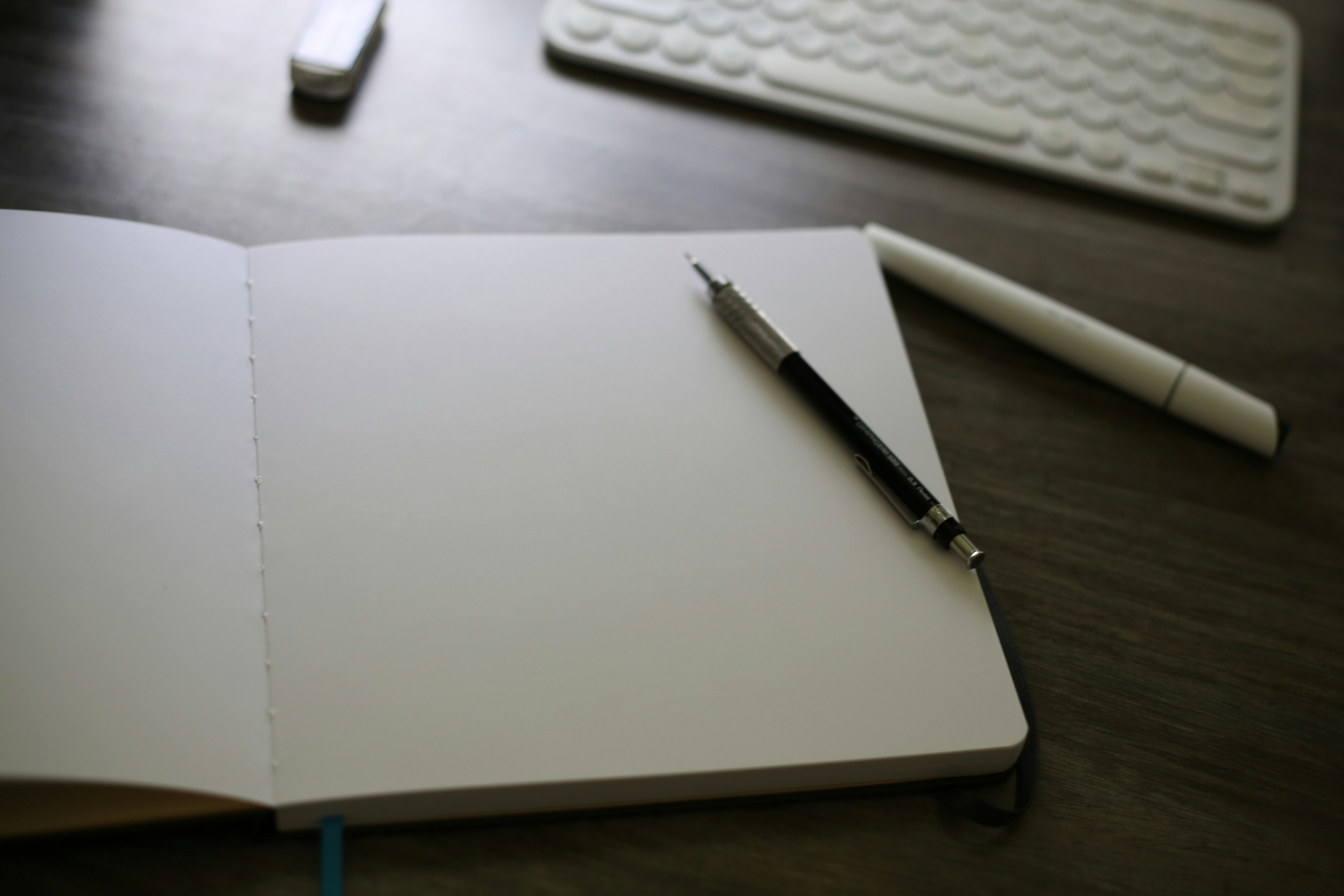 Open notebook beside keyboard on desk