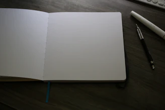 An open notebook sitting on a desk next to a keyboard