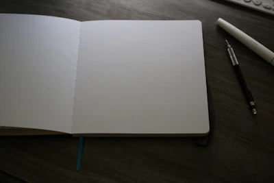 An open notebook sitting on a desk next to a keyboard