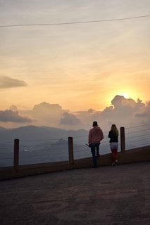 A couple of people that are standing near a fence