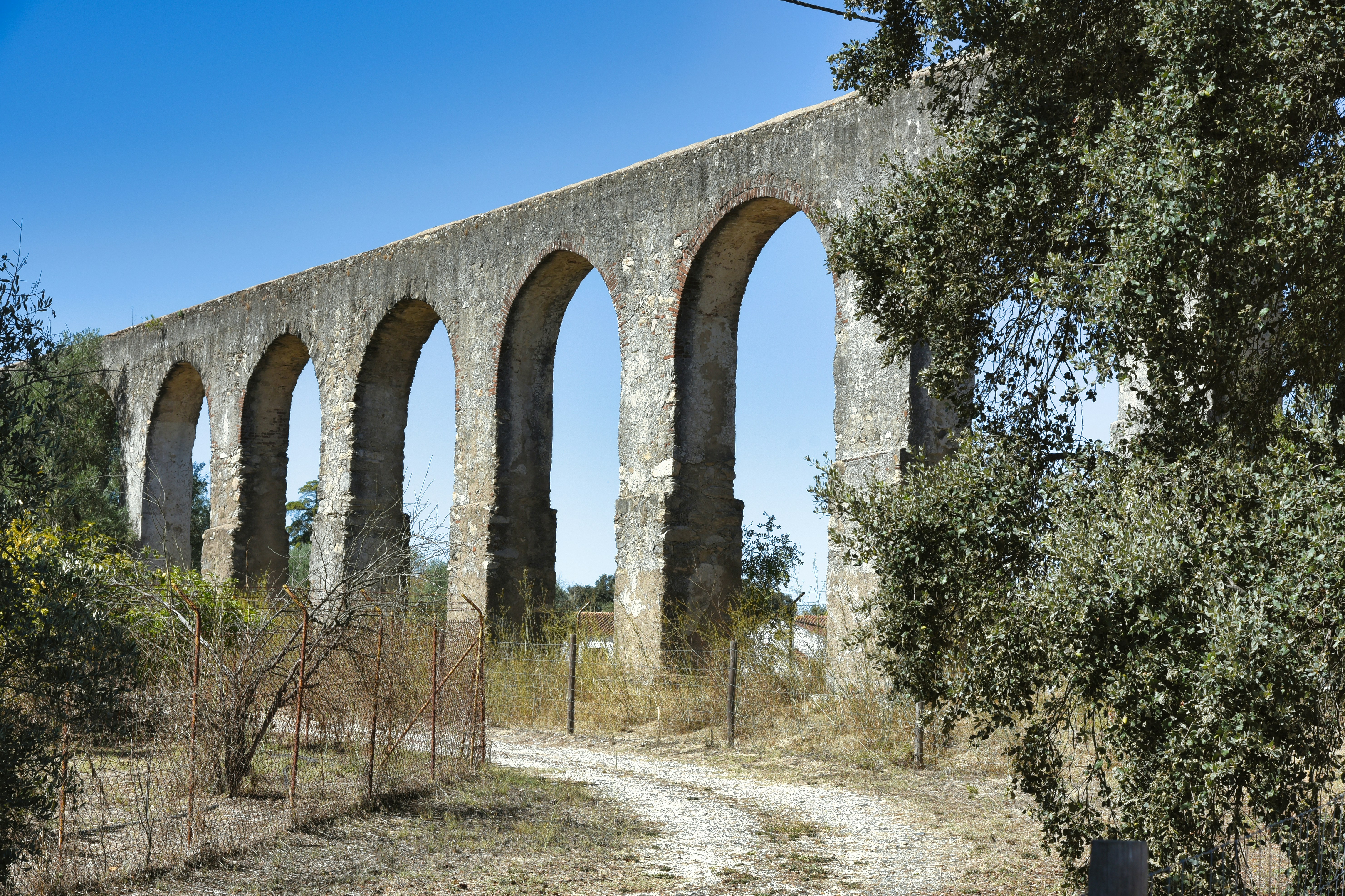 A stone bridge over a dirt road surrounded by trees