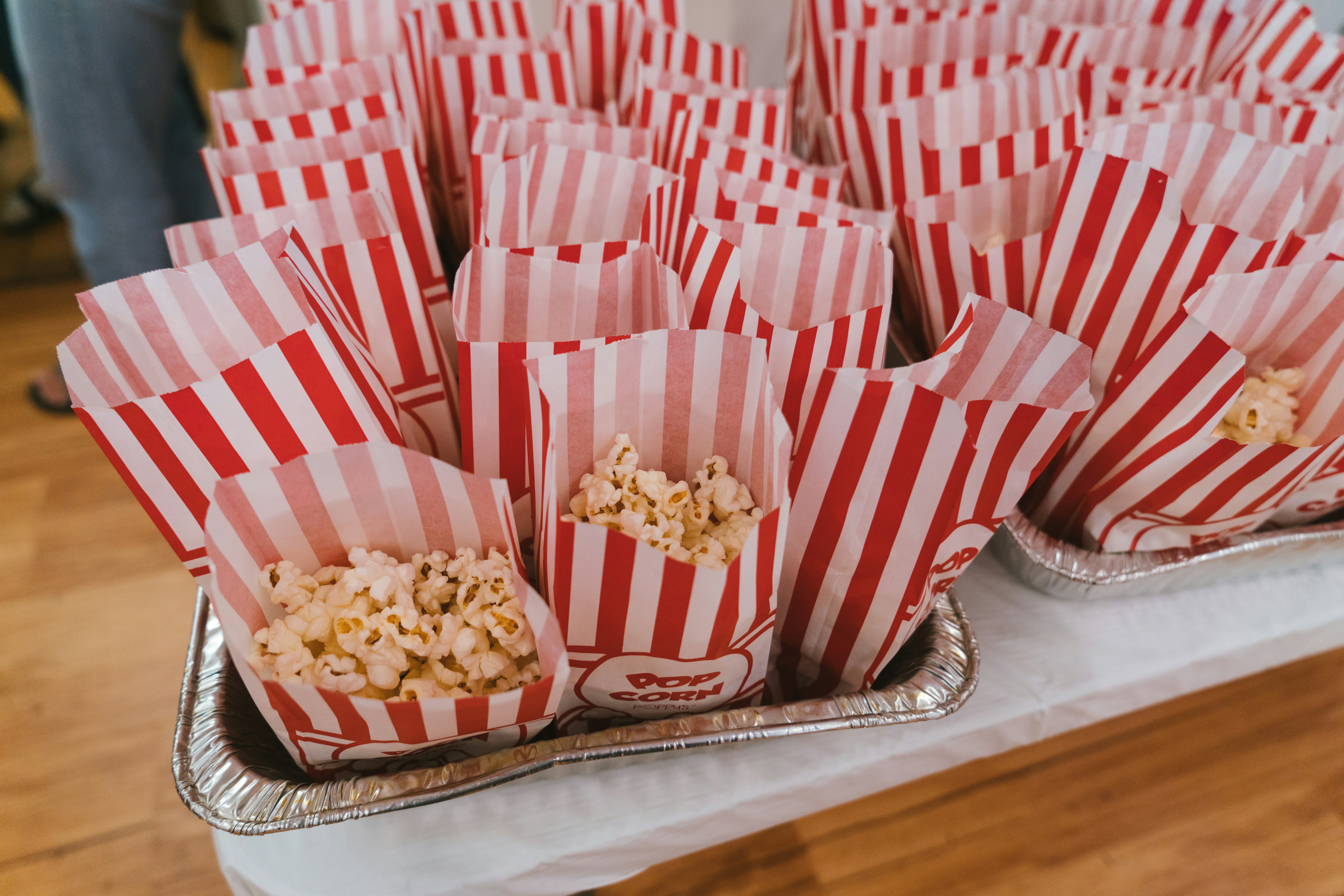A table topped with red and white striped bags of popcorn