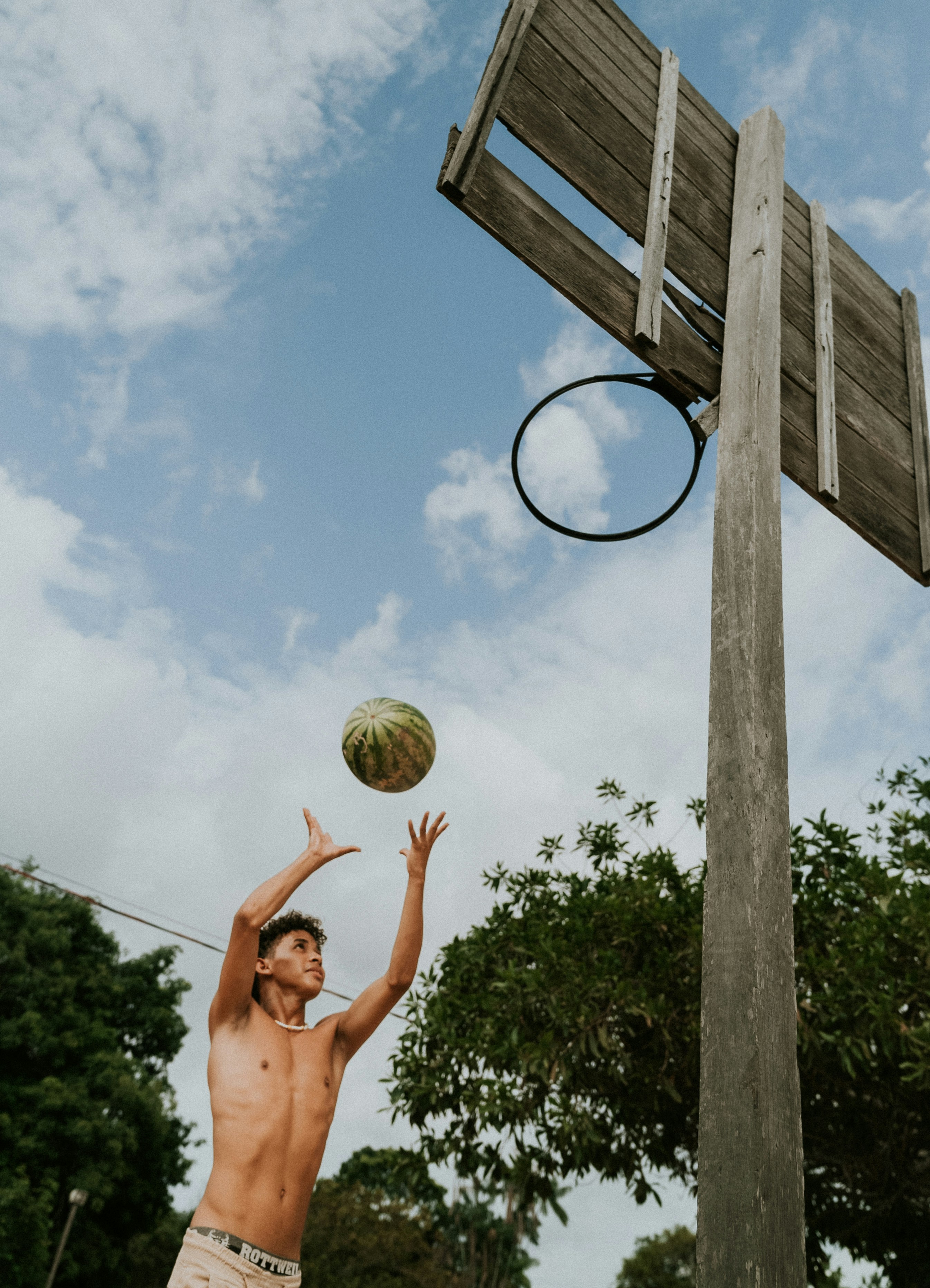 A shirtless man playing basketball in a park