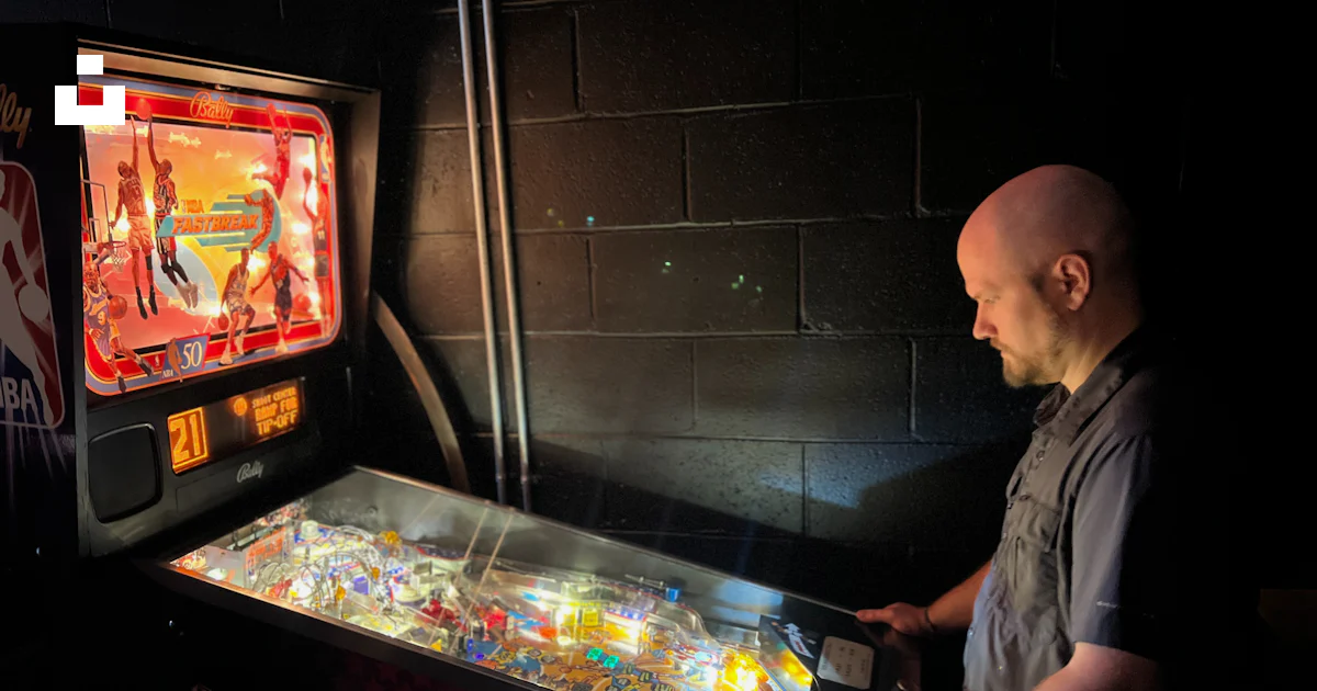 A man standing next to a pinball machine photo – Free Man Image on Unsplash