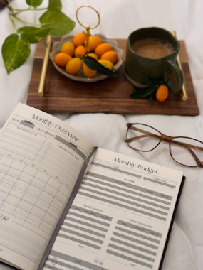 An open book sitting on top of a bed next to a bowl of oranges