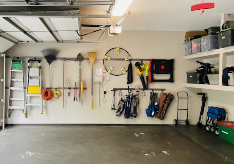 A garage wall fitted with pegboard and shelving to organize tools and equipment