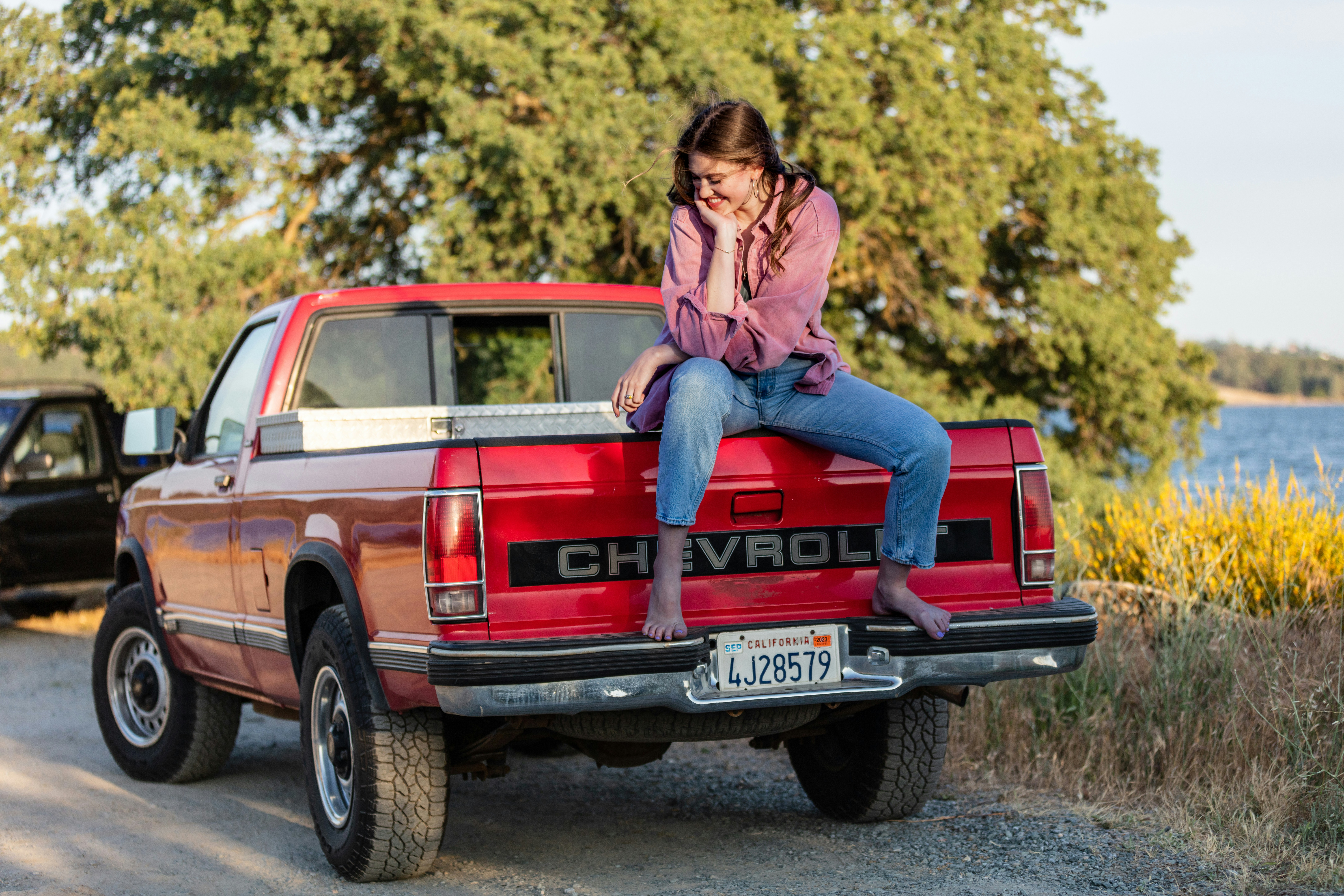 Una mujer sentada en la parte trasera de una camioneta roja