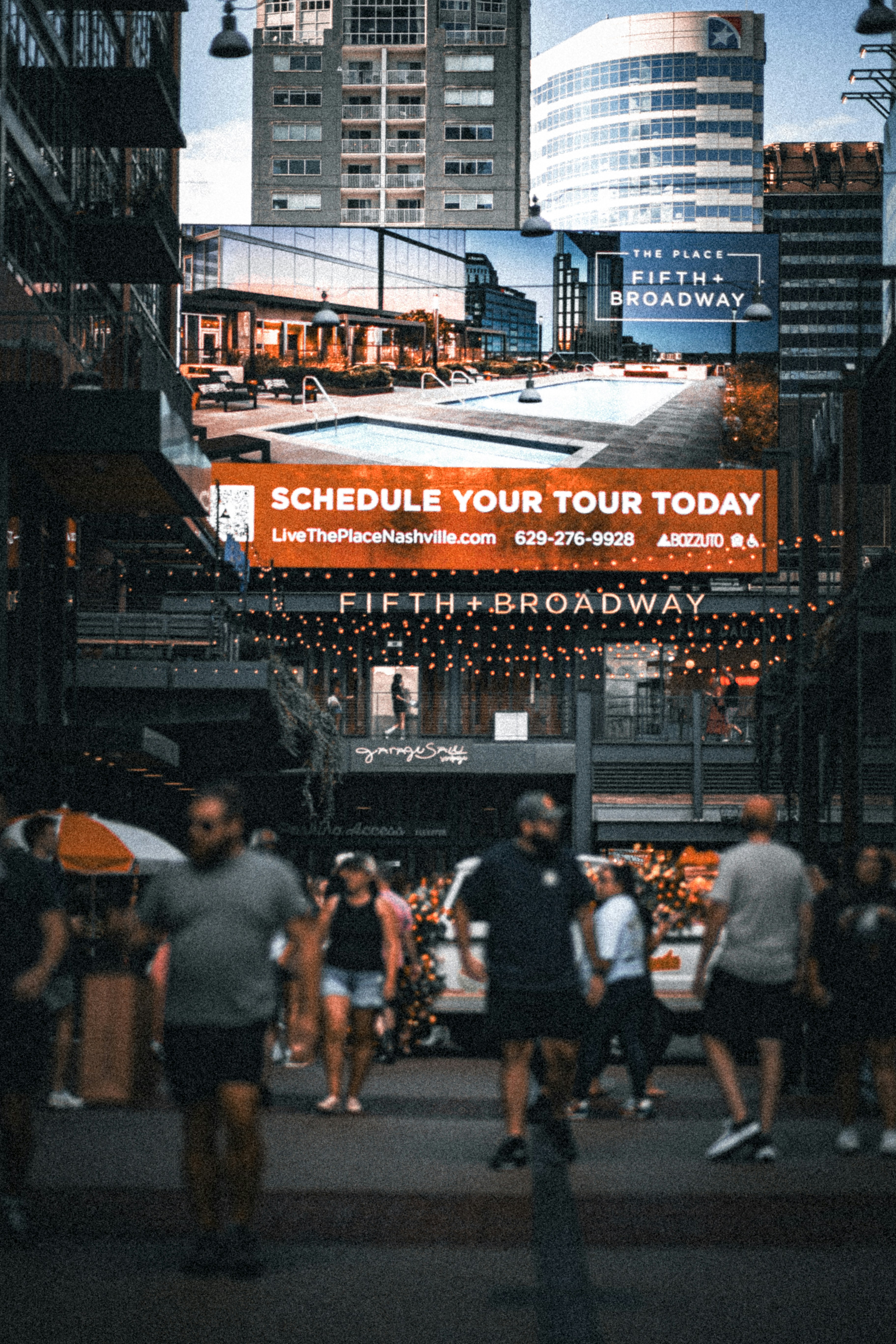 A group of people walking down a street next to tall buildings