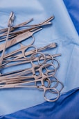 A pile of surgical scissors on a blue cloth