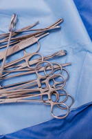 A pile of surgical scissors on a blue cloth