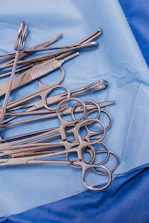 A pile of surgical scissors on a blue cloth