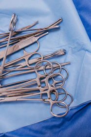 A pile of surgical scissors on a blue cloth