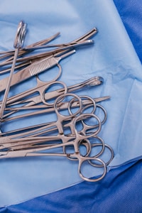 A pile of surgical scissors on a blue cloth