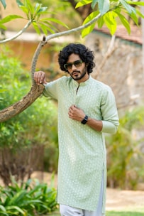 A man standing next to a tree wearing a green shirt