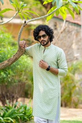 A man standing next to a tree wearing a green shirt