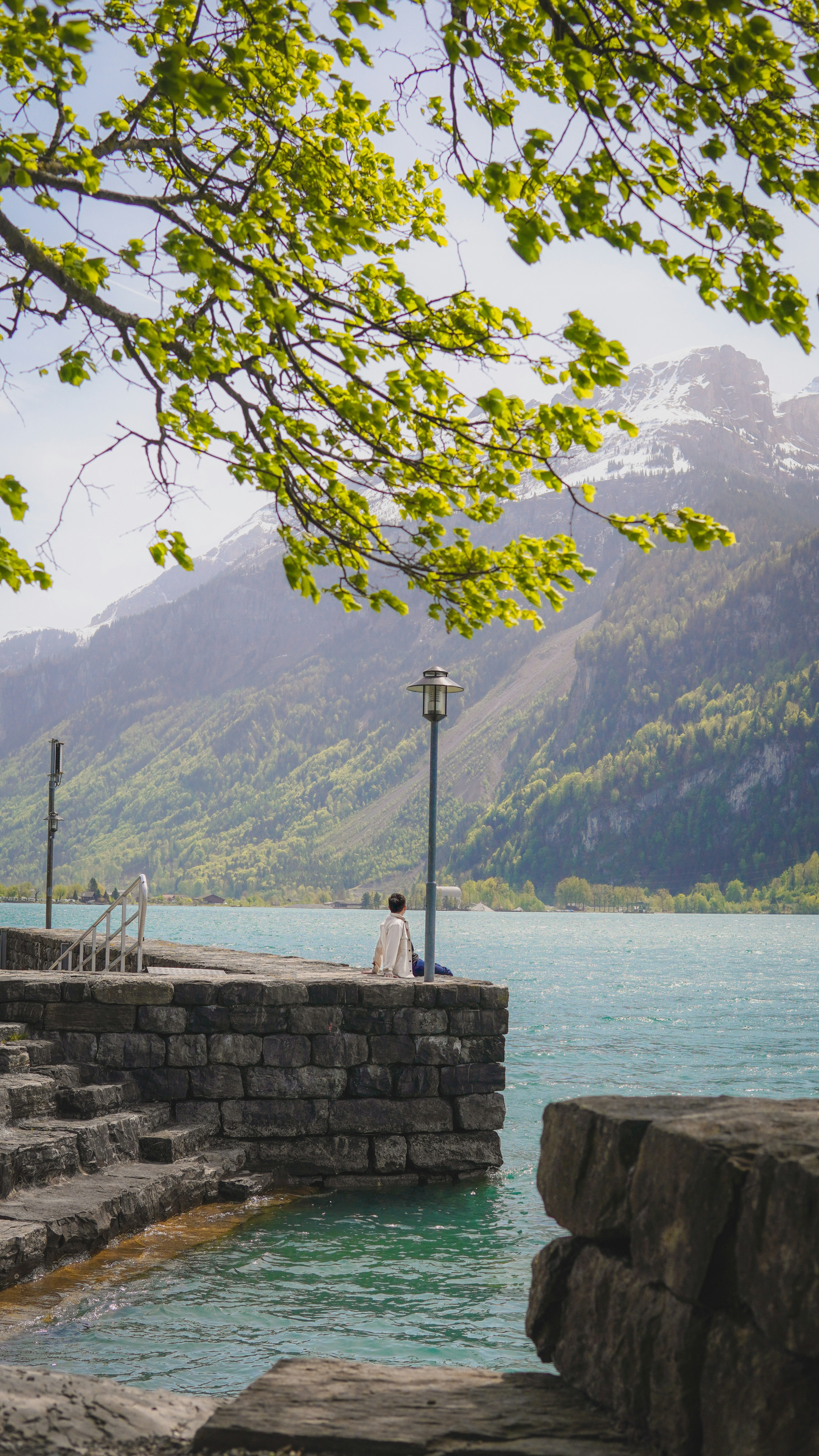 Un homme assis sur un mur de pierre à côté d’un plan d’eau
