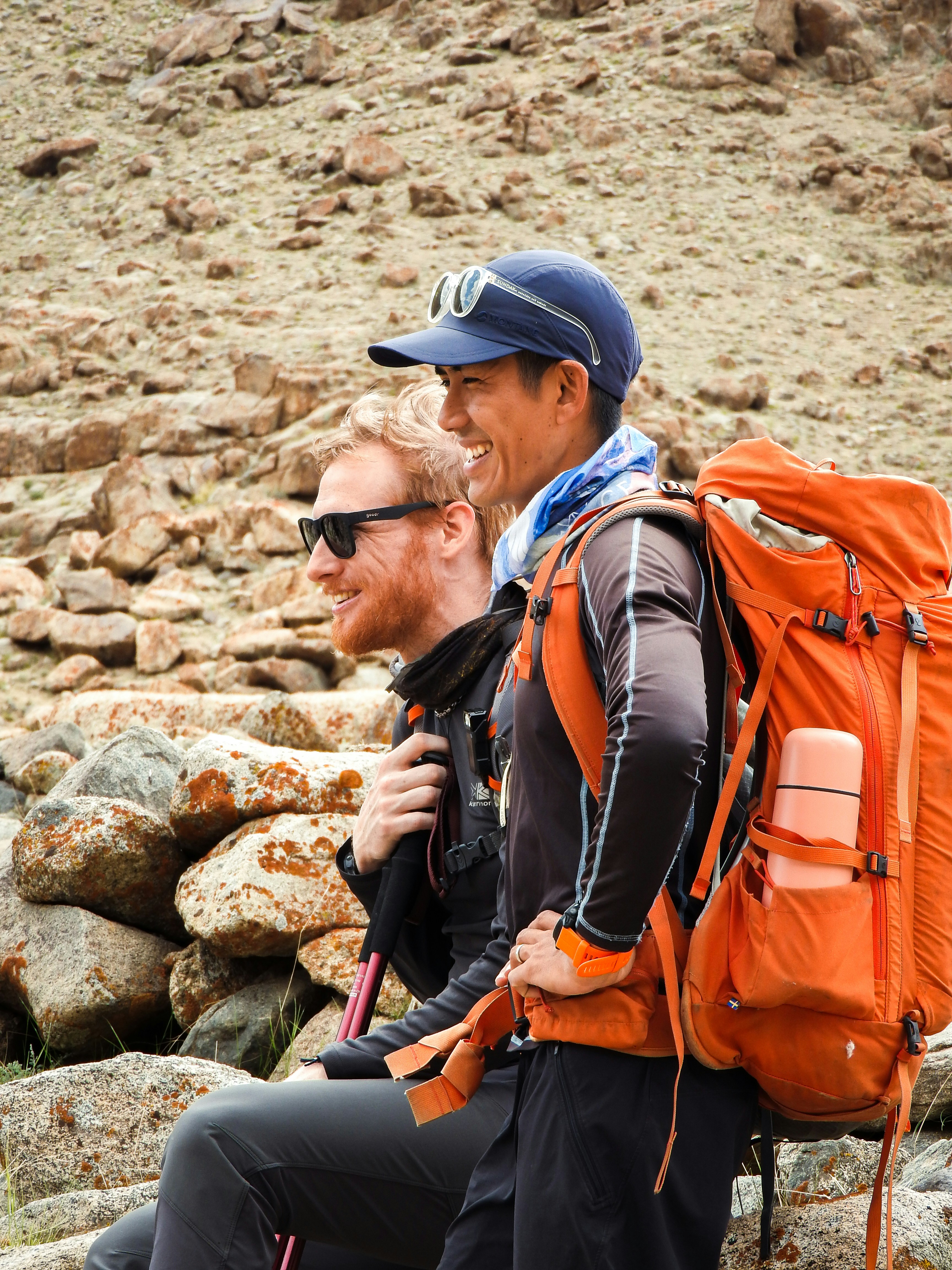 Two young backpackers with hiking gear smiling at camera in Australian outback landscape