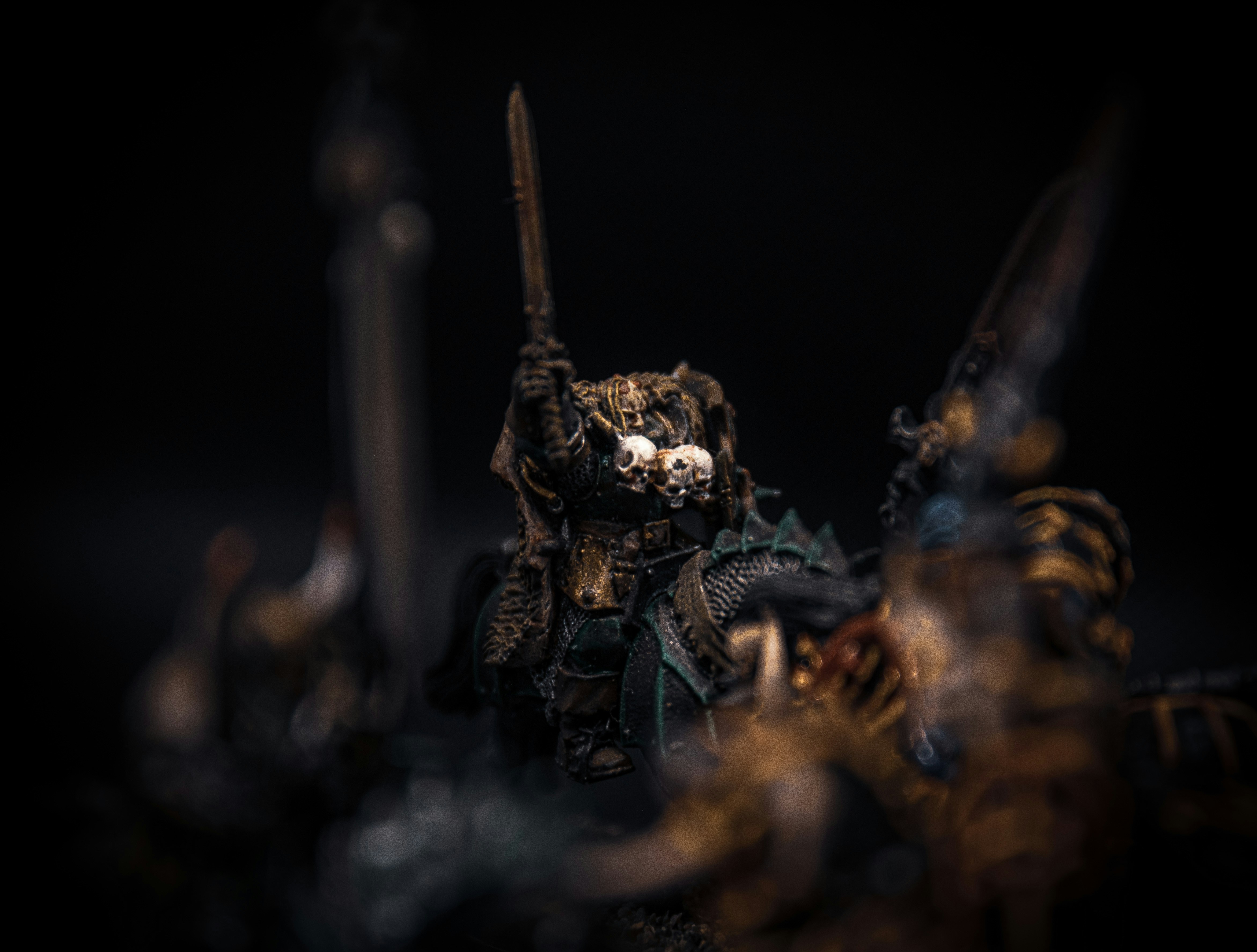 A hand-painted fantasy miniature warrior holds a sword aloft.