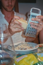 A man holding a grater over a plate of food