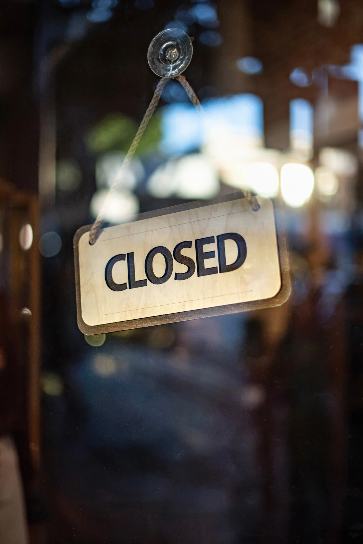A closed sign hanging on a glass shop door