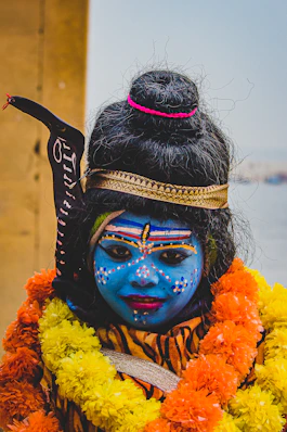 A woman with blue face paint and a garland around her neck