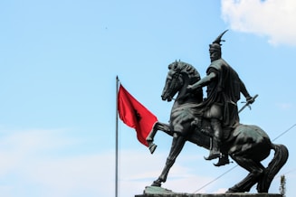 A statue of a man on a horse with a red flag