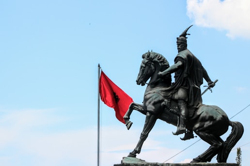 A statue of a man on a horse with a red flag