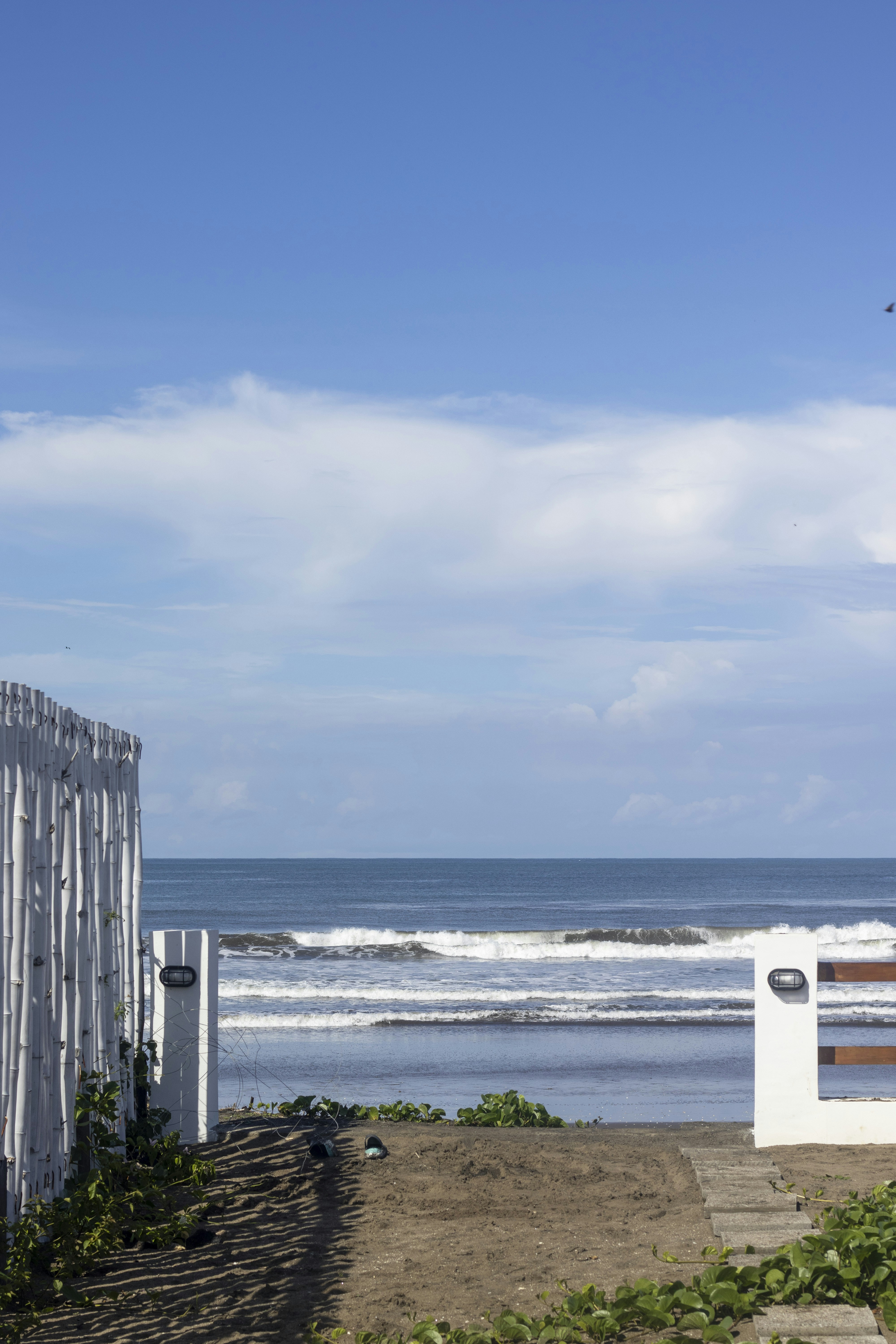 Une plage avec une clôture blanche et un océan en arrière-plan