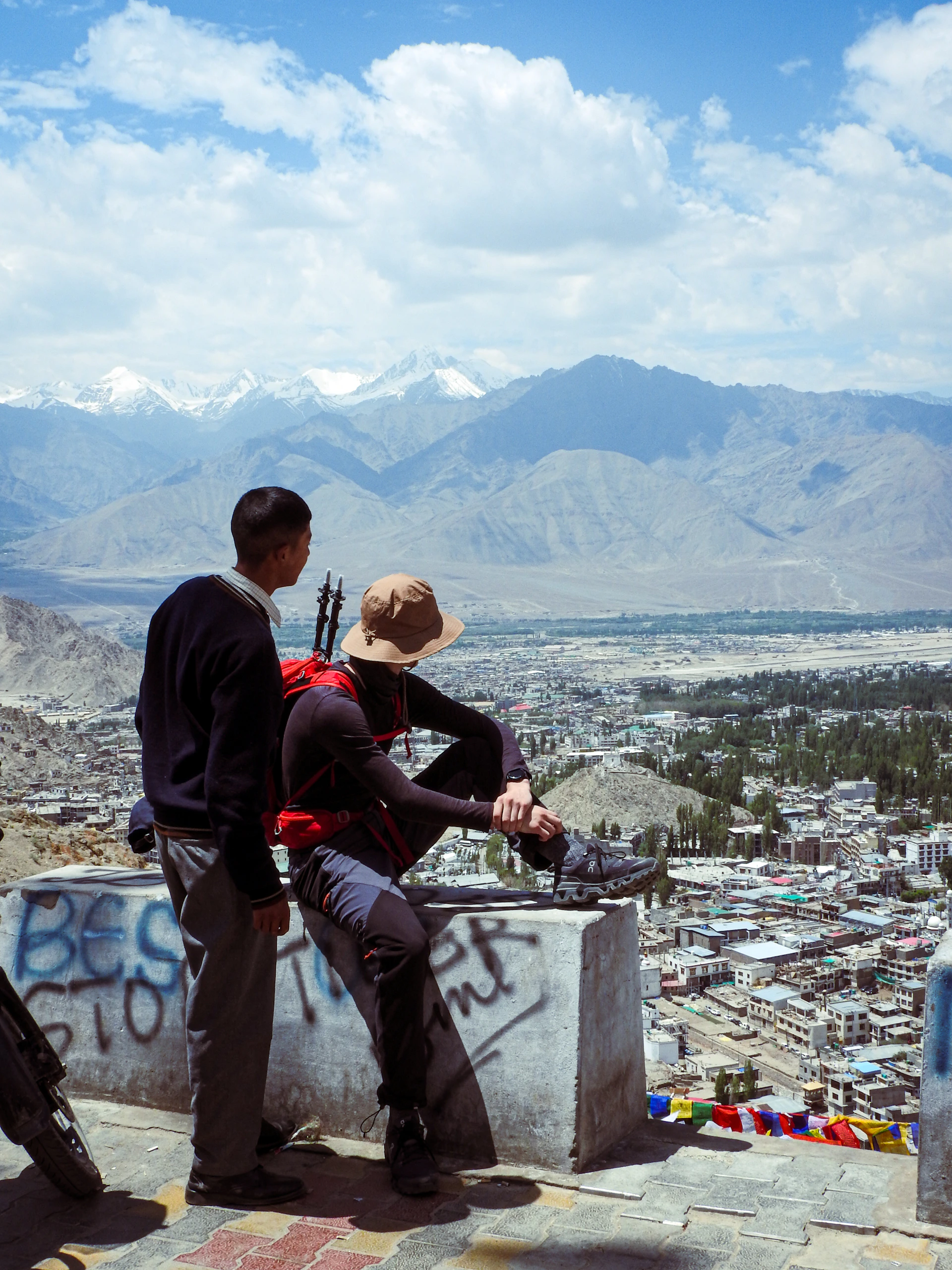 A couple of people sitting on top of a cement wall