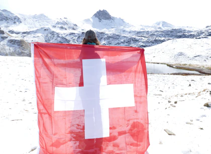 A person holding a swiss flag in the snow