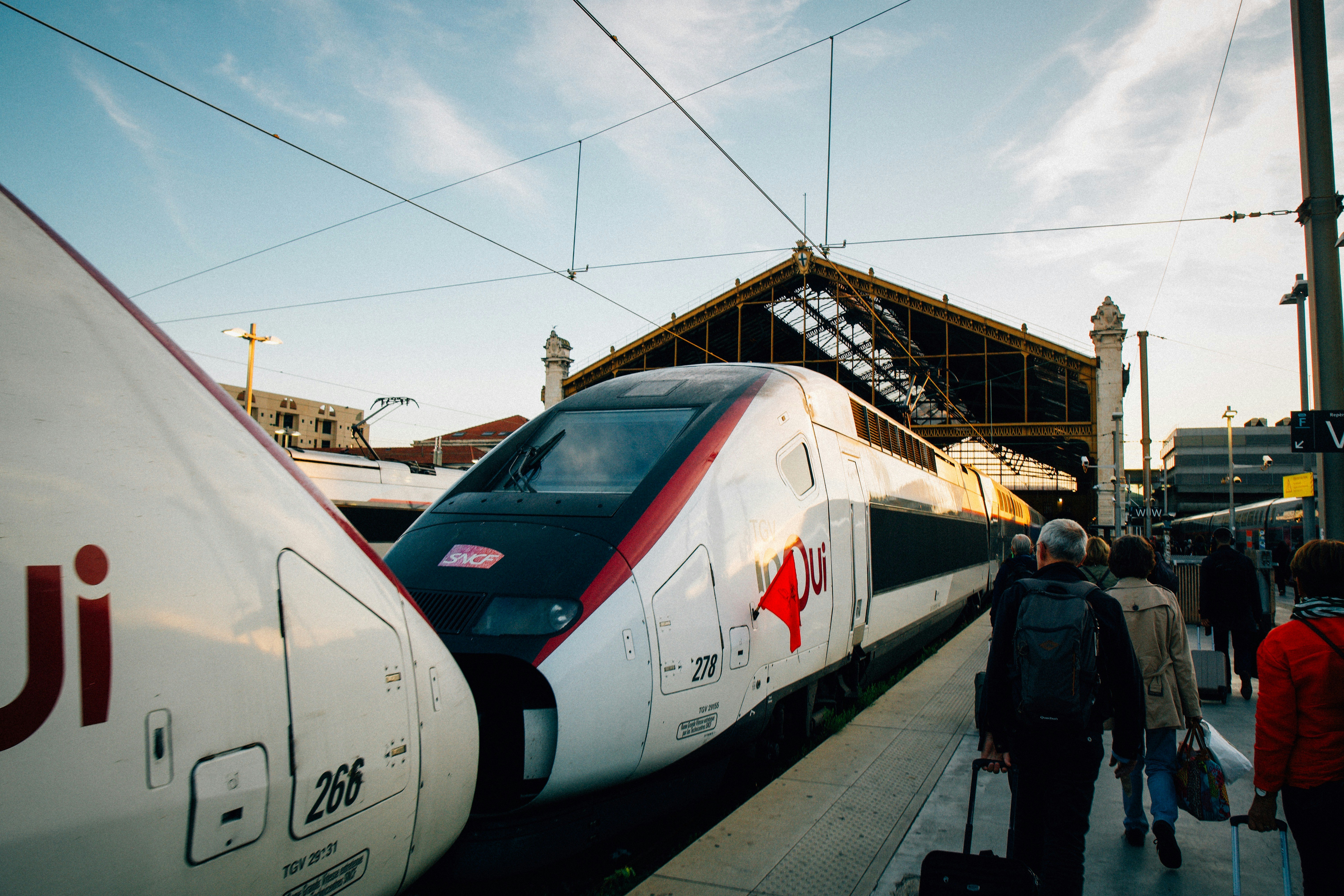 A group of people standing next to a train, Travel via Interrail with the famous TGV in Marseille, France during summer