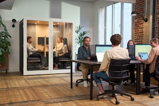 A group of people sitting around a table working on computers