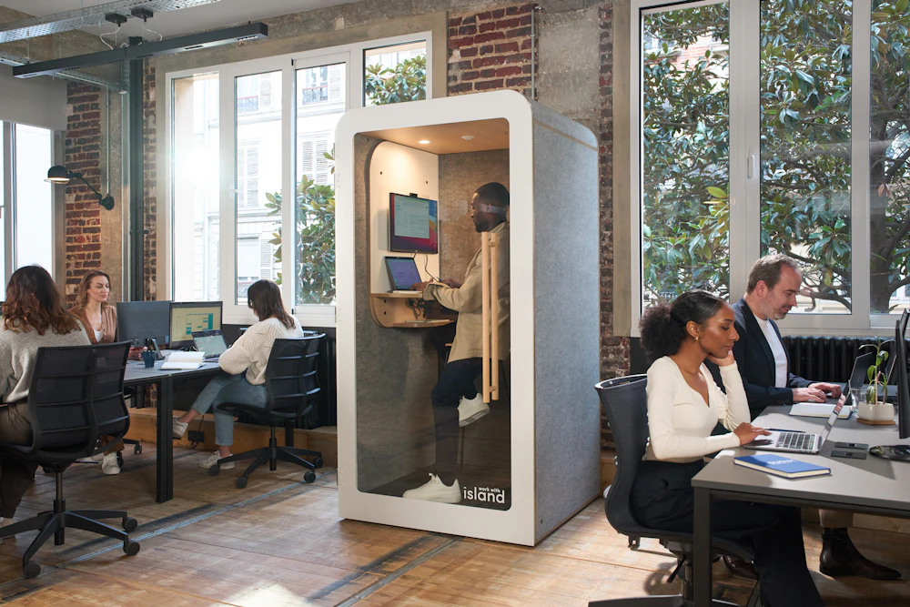Members working at long shared desks on the open studio floor