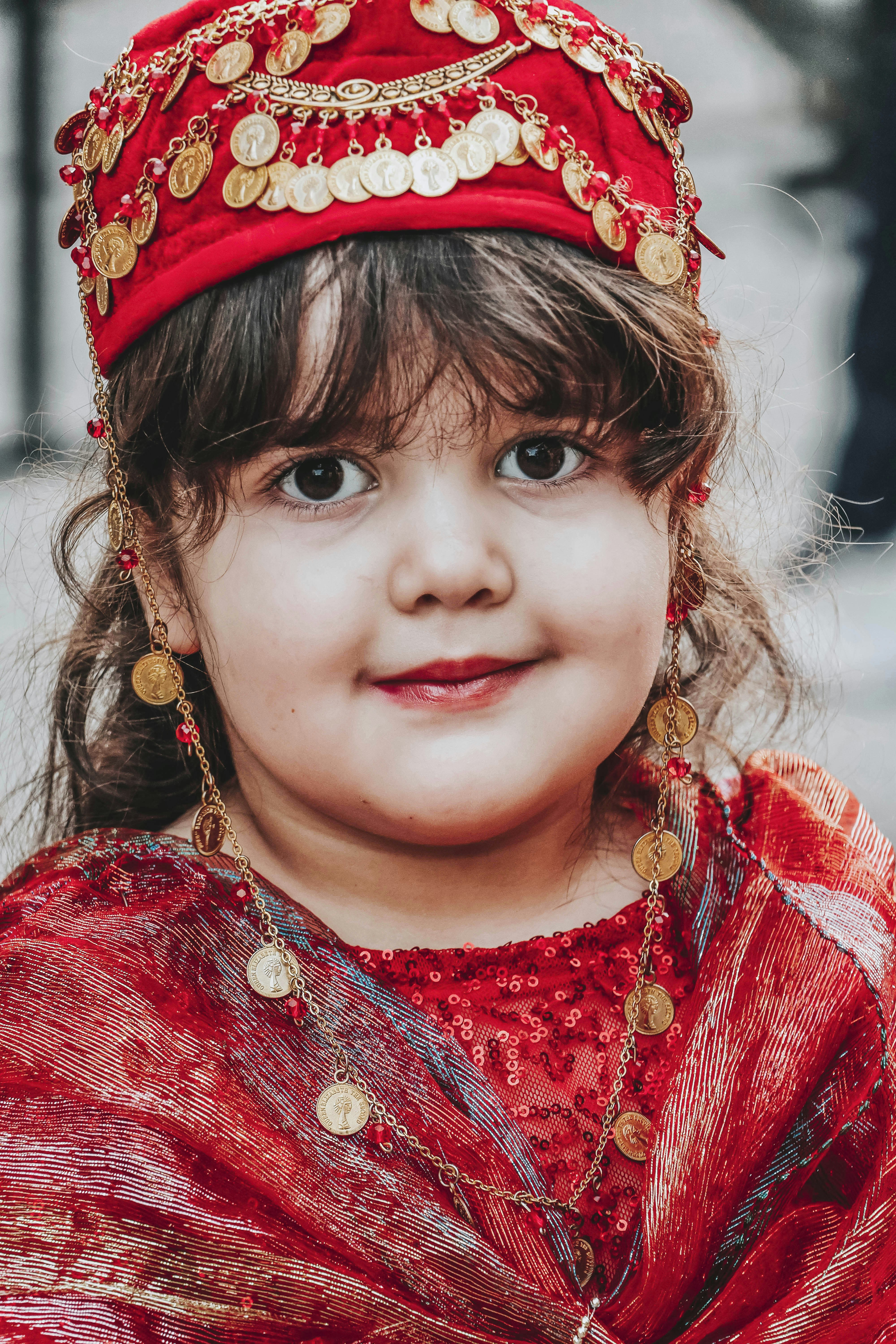 A little girl wearing a red dress and a red headdress