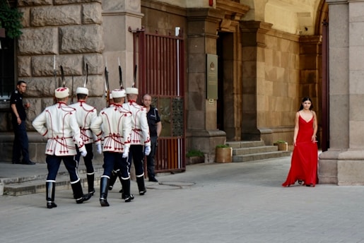 A woman in a red dress standing in front of a group of uniformed men