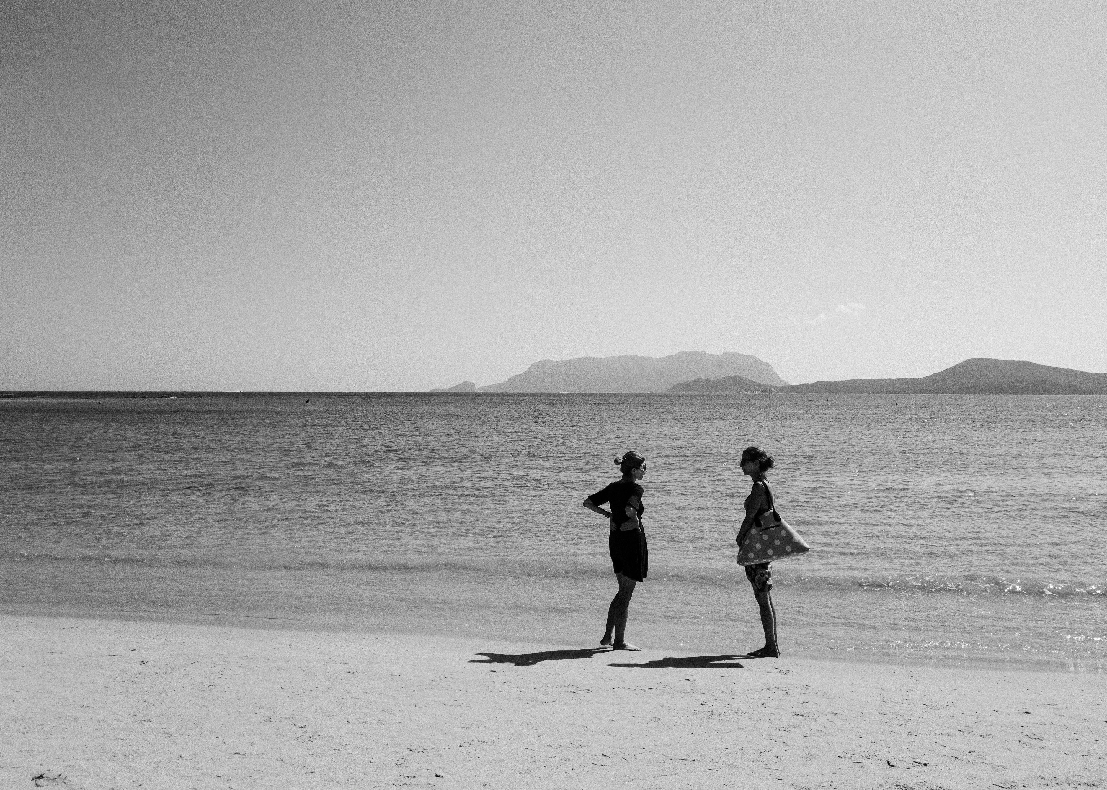 A couple of people standing on top of a sandy beach
