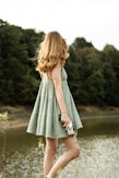 A woman in a green dress standing by a lake