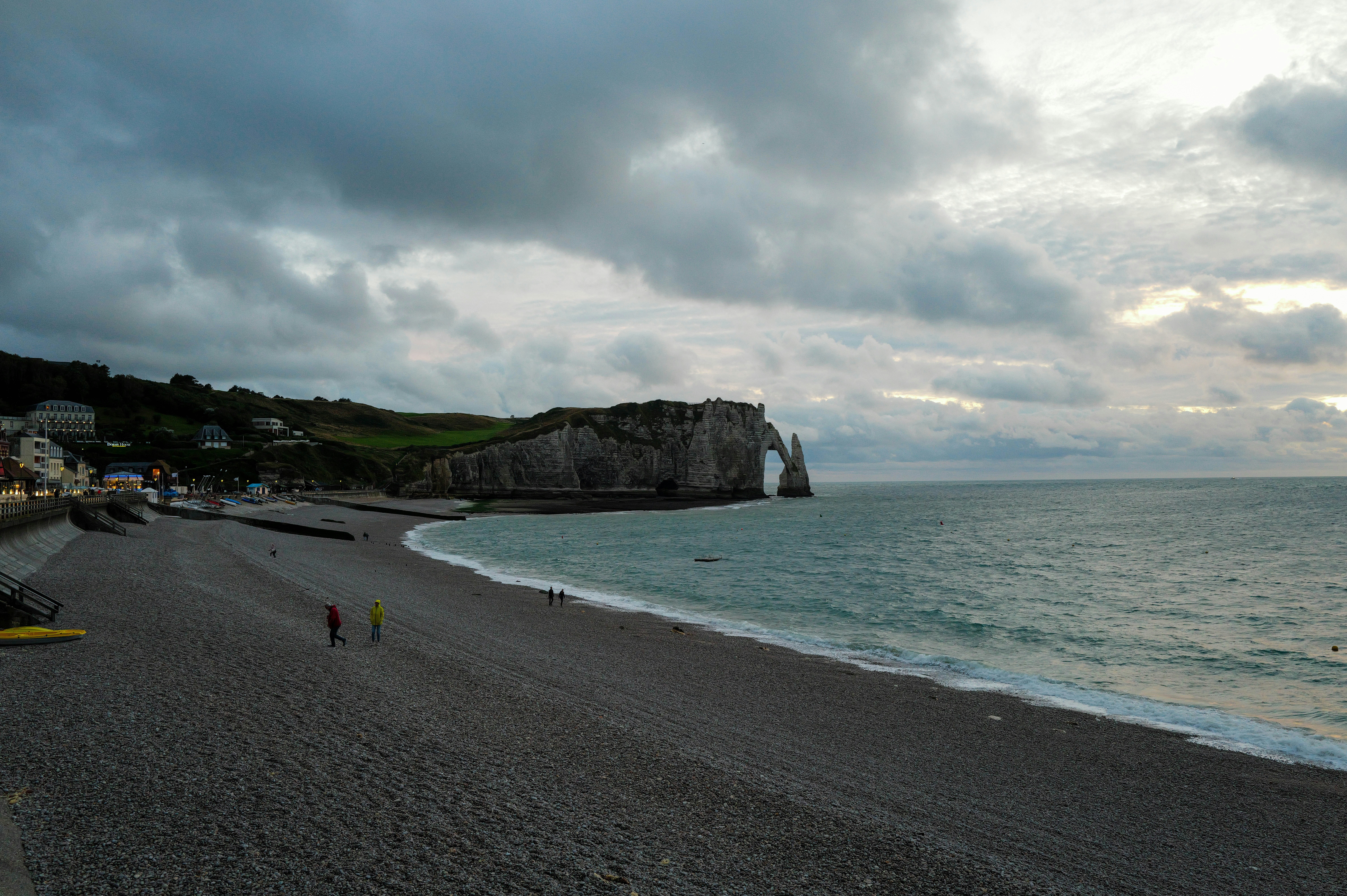 A couple of people walking on a beach next to the ocean