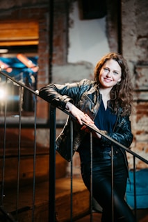 A woman in a leather jacket leaning on a railing