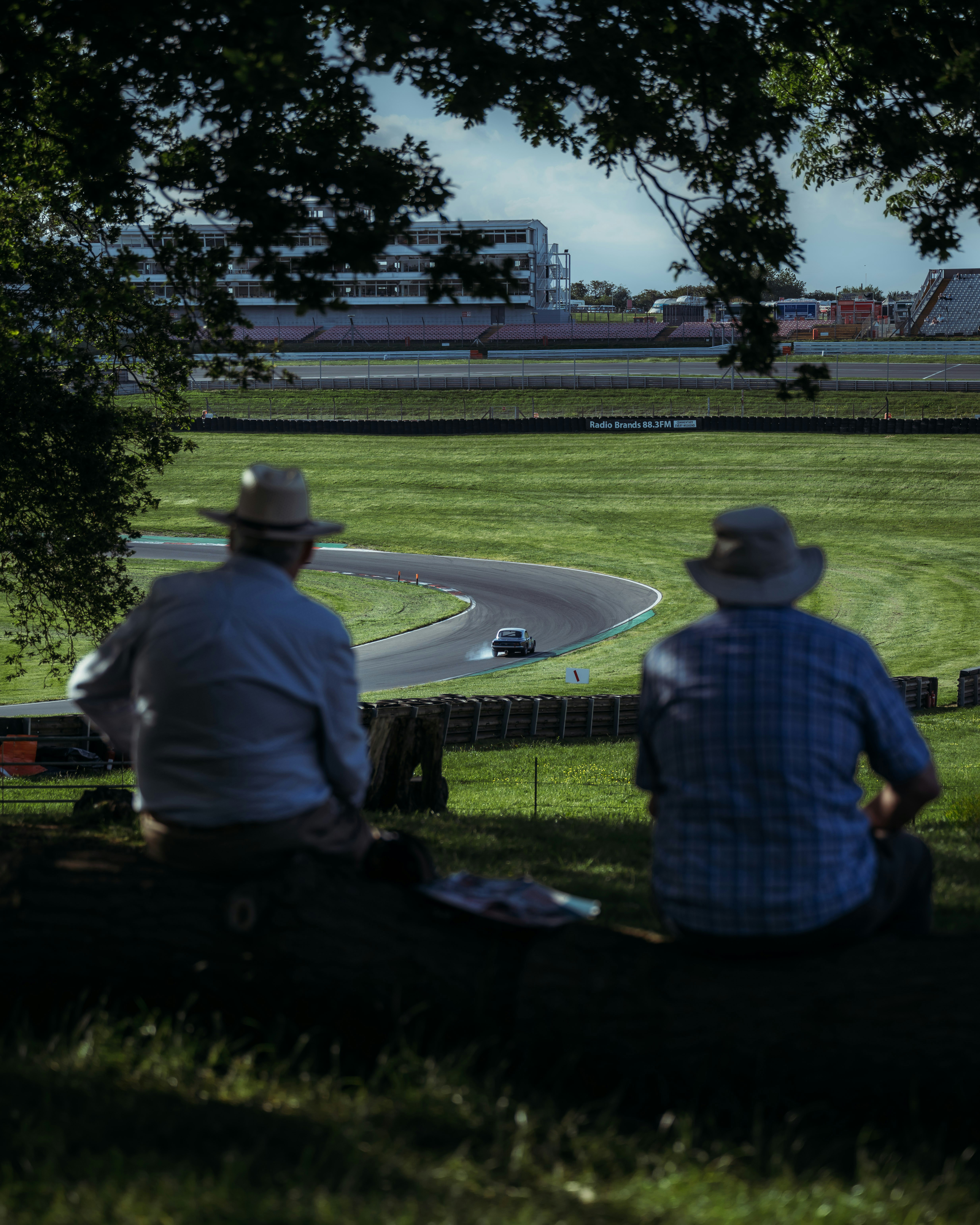 Two men sitting on a bench watching a race