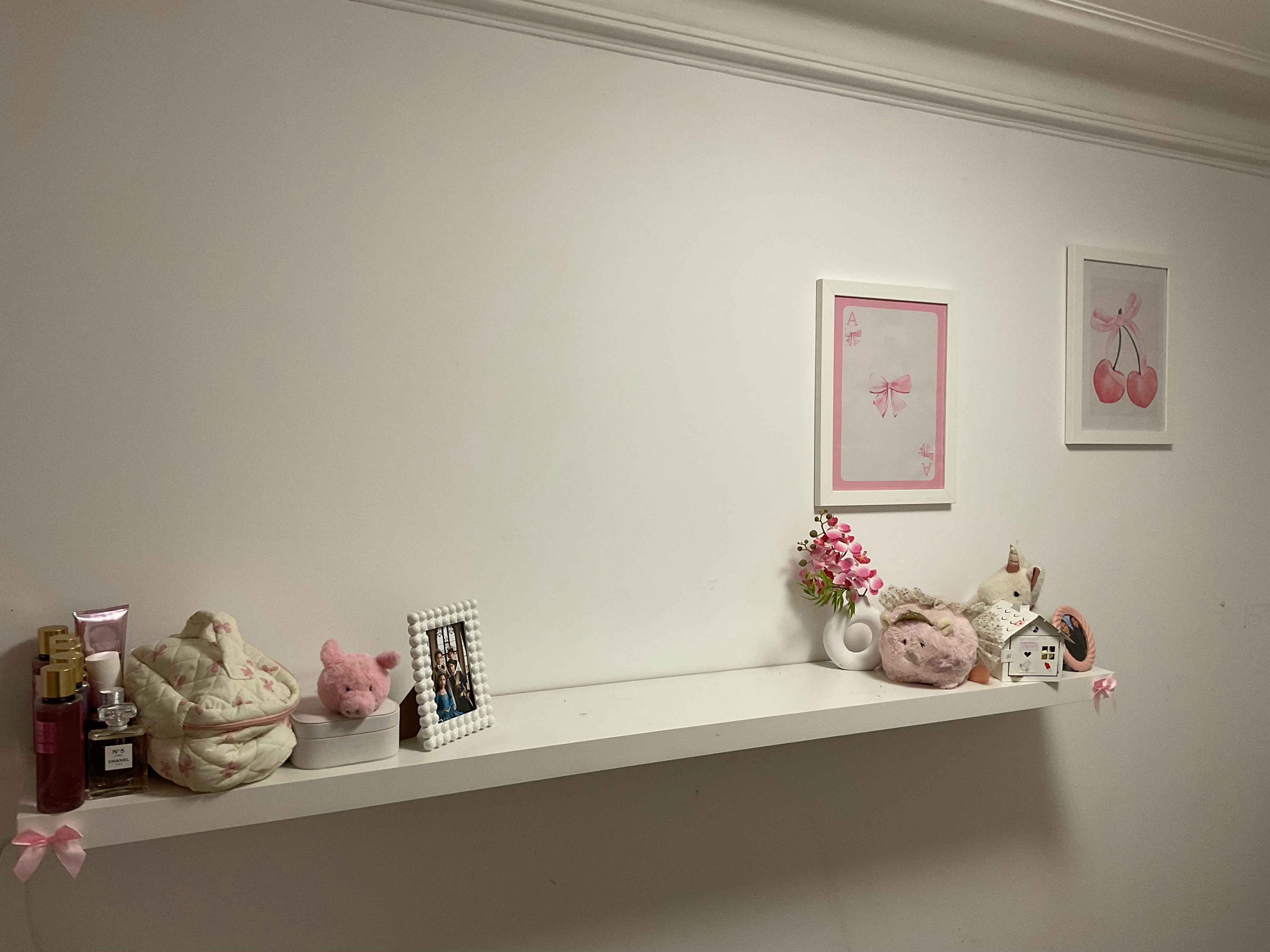 Soft plush teddy bears and colorful dolls arranged on pastel pink shelf