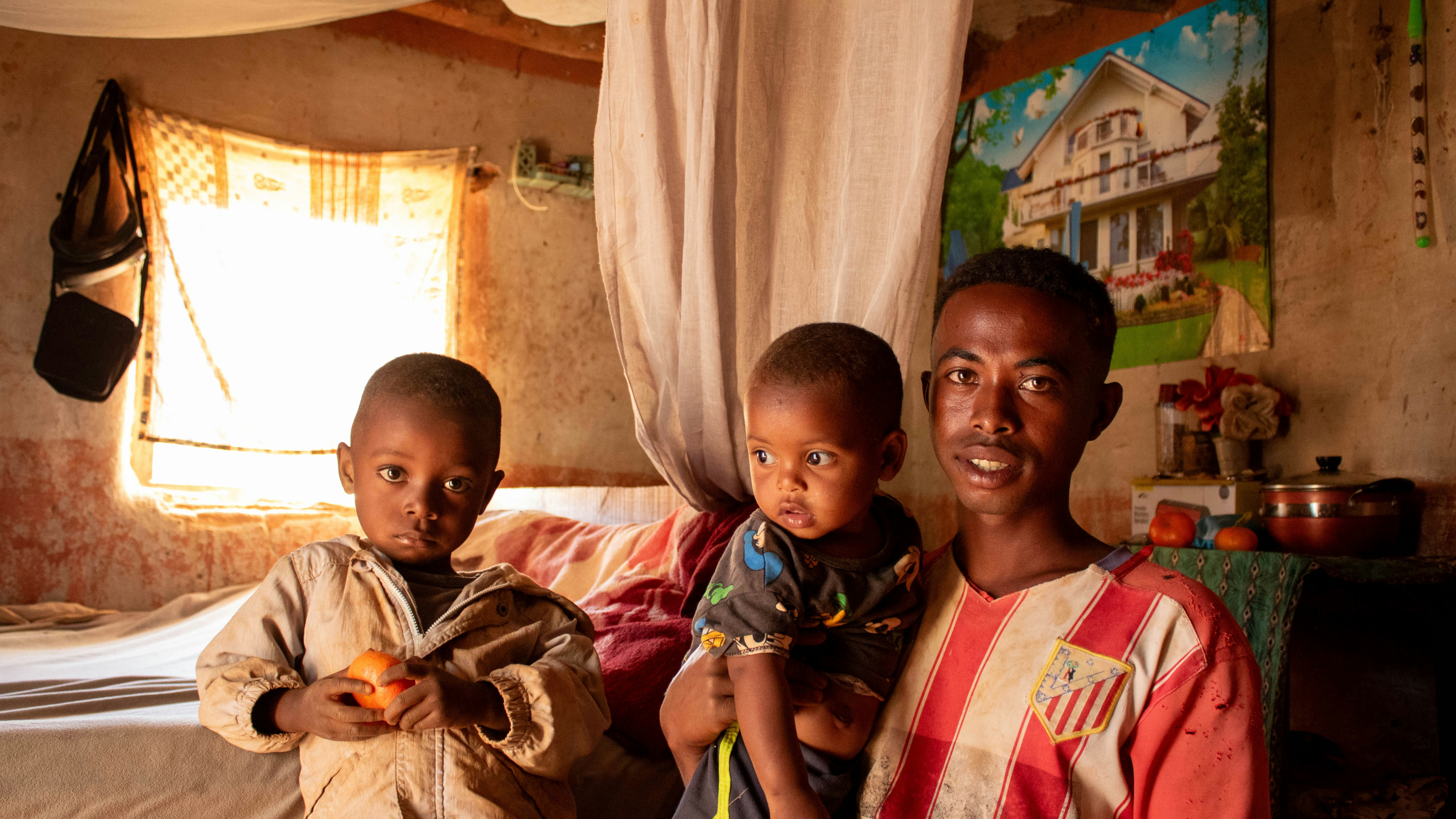 A man and two children standing in a bedroom
