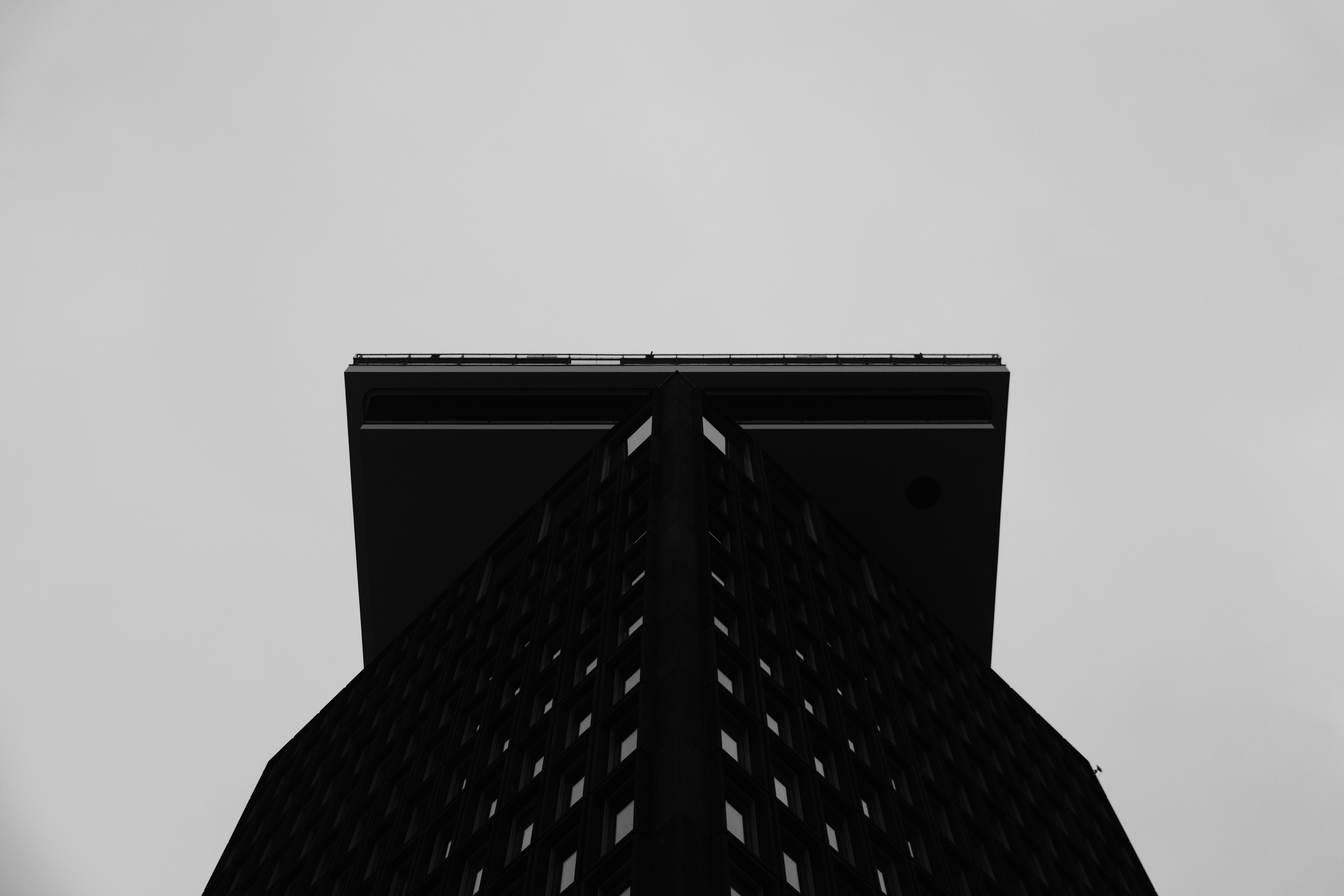Modern architectural structure photographed from below, geometric lines converging against deep grey sky, minimal and bold