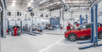 Mechanics working on cars in a bright, spacious automotive repair workshop