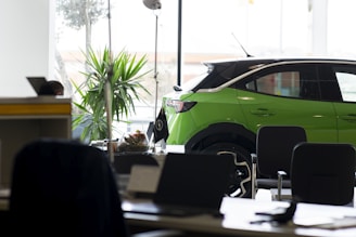 A green car is parked in an office