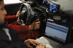 A man sitting in a car using a laptop computer